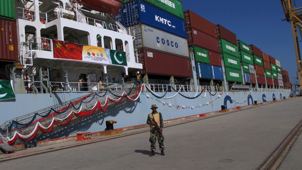 A Pakistan Navy soldier stands guard while a loaded Chinese ship prepares to depart, at Gwadar port [Muhammad Yousuf/AP Photo]