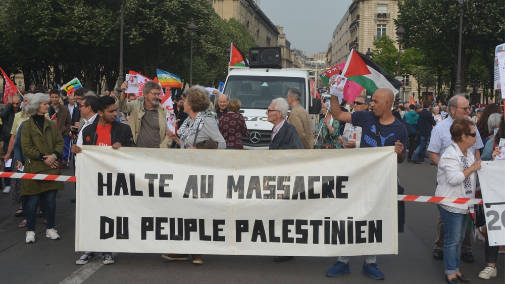 Protesters carry a sign that reads 'Stop the massacre of the Palestinian people' [Lucas Radicella/Al Jazeera]