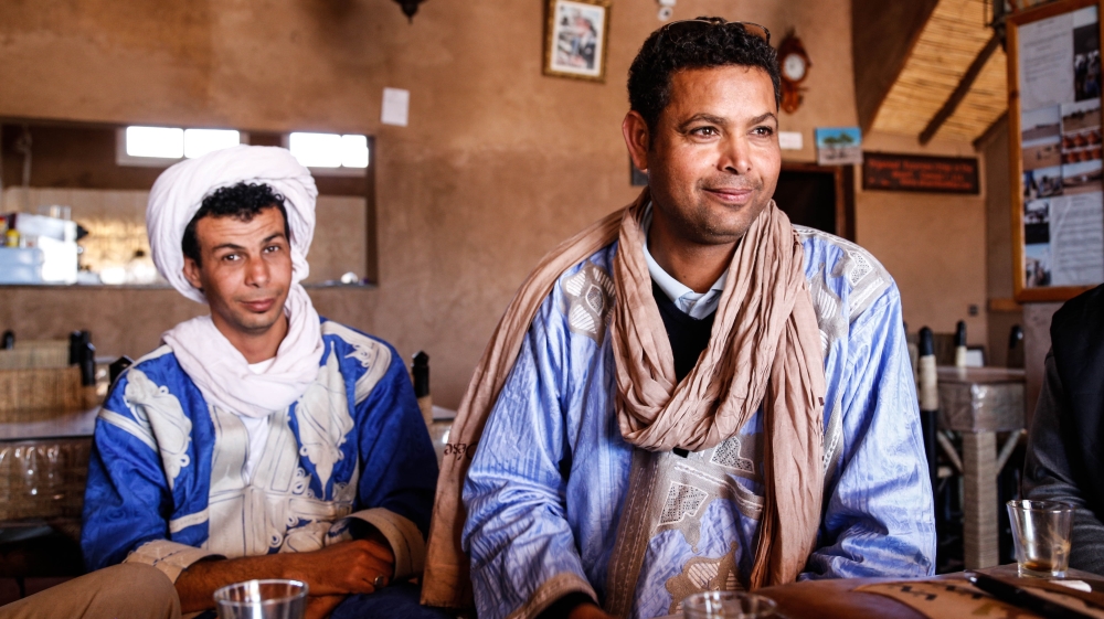 Sbai, right, talks with locals in a cafe in the centre of M'hamid [Viktorija Mickute/Al Jazeera]