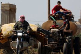 A man rides a motorbike with belongings in Deraa countryside