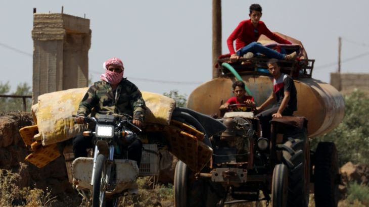 A man rides a motorbike with belongings in Deraa countryside