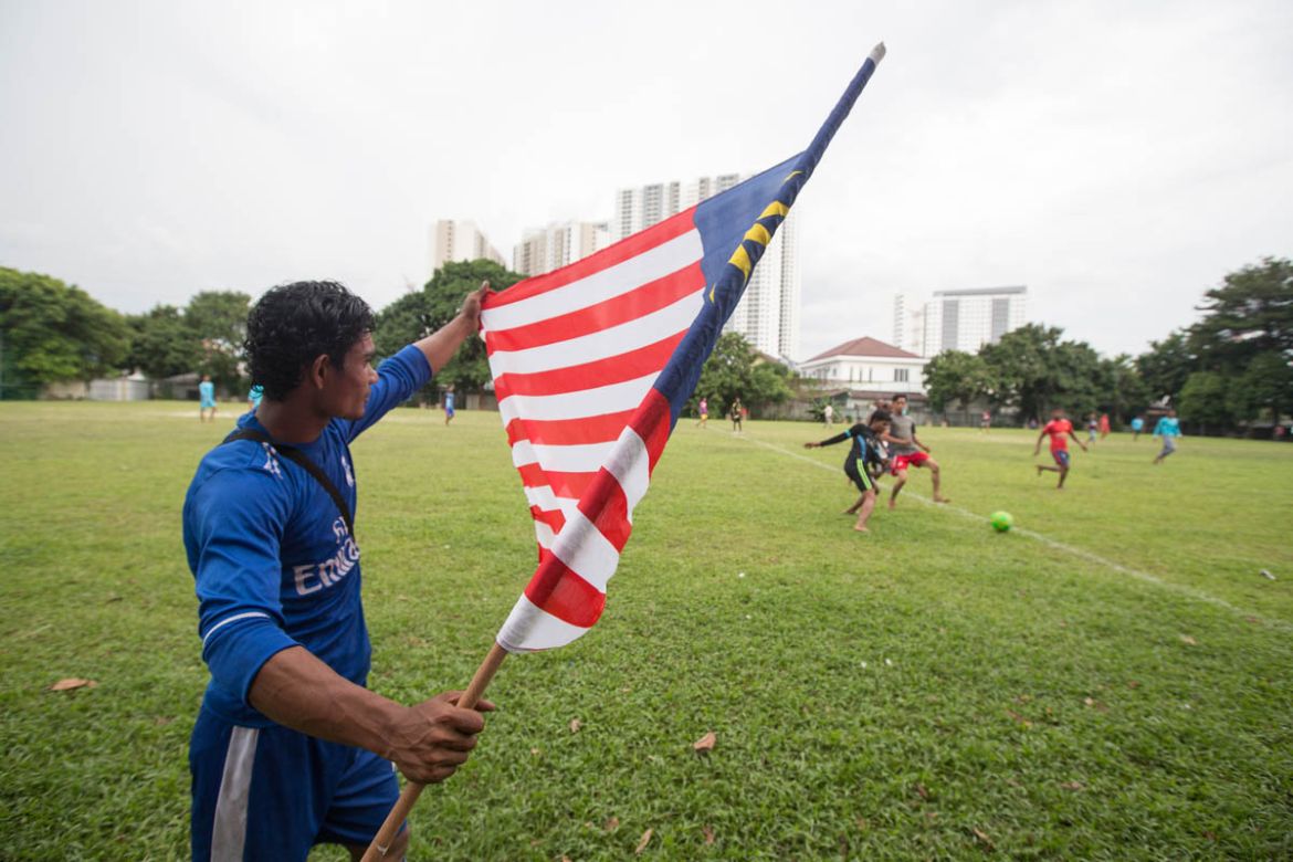 A Rohingya man unfolds the Malaysian flag during the warmup session. A large number of the Rohingya living in Malaysia have arrived during the last 30 years, raising families here. Their children are