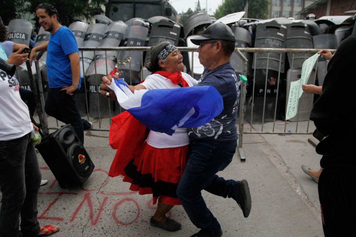 A couple dances in front of the police barricade during a protest in Tegucigalpa, Honduras, Saturday June 2, 2018. Members of the Opposition Alliance Against the Dictatorship marched the streets in pr