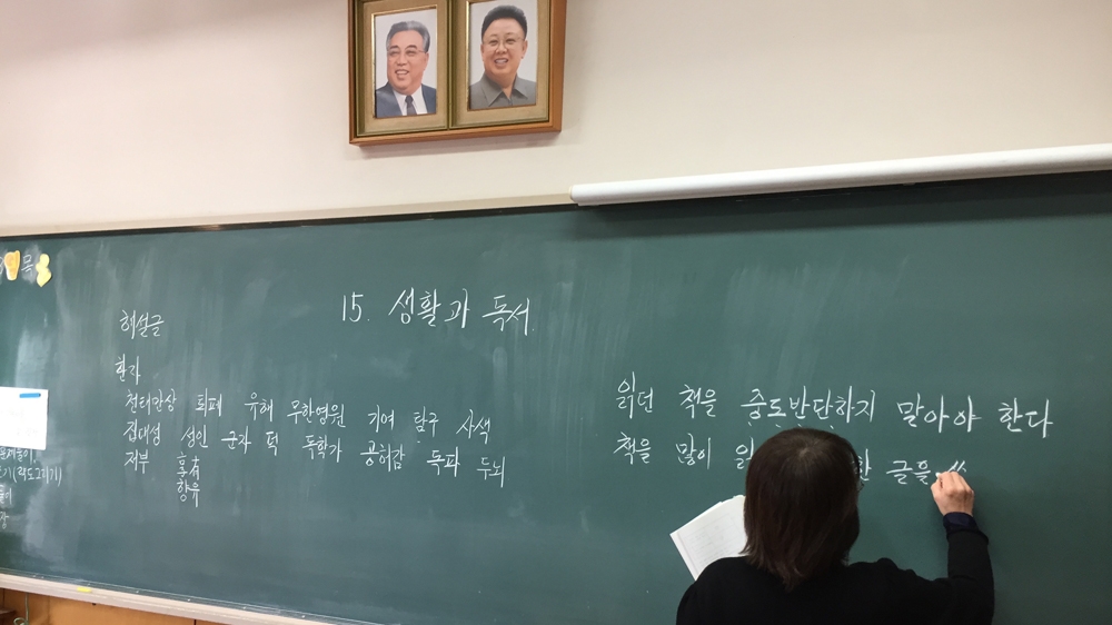 Portraits of North Korea's former leaders Kim Jong-il and Kim Il-sung hang above the blackboards at Song's Korean school, where lessons are taught in both Korean and Japanese [Al Jazeera]