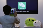 A man takes a photograph of a counter promoting WeChat, a product of Tencent, displayed at a news conference in Hong Kong on March 18, 2015 [Reuters]