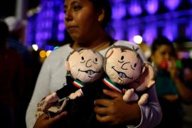 A supporter of presidential candidate Andres Manuel Lopez Obrador holds dolls depicting him as she waits for the presidential election results in downtown Mexico City, Mexico July 1, 2018. REUTERS/Ale