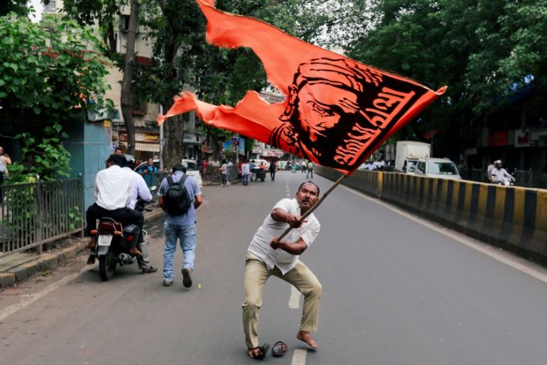 A man waves a flag as he blocks a road during a protest, organised by Maharashtra state''s Maratha community, to press their demands for reserved quotas in government jobs and college places for studen