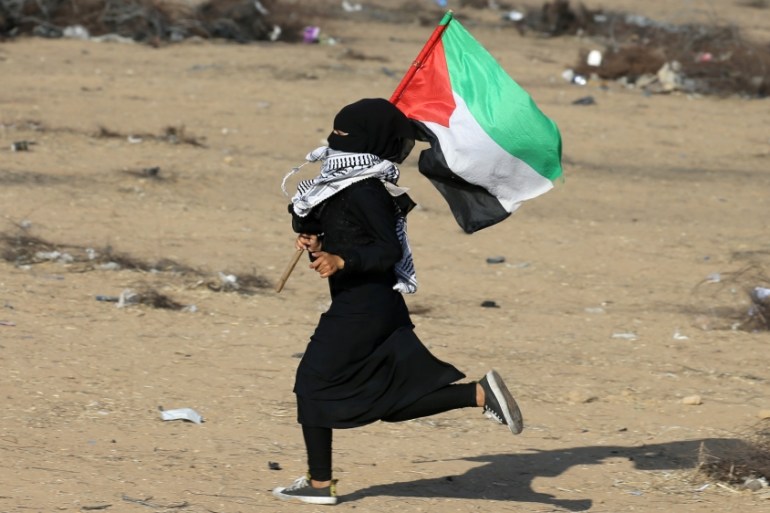 Palestinian girl runs with a Palestinian flag during a protest at the Israel-Gaza border in the southern Gaza Strip