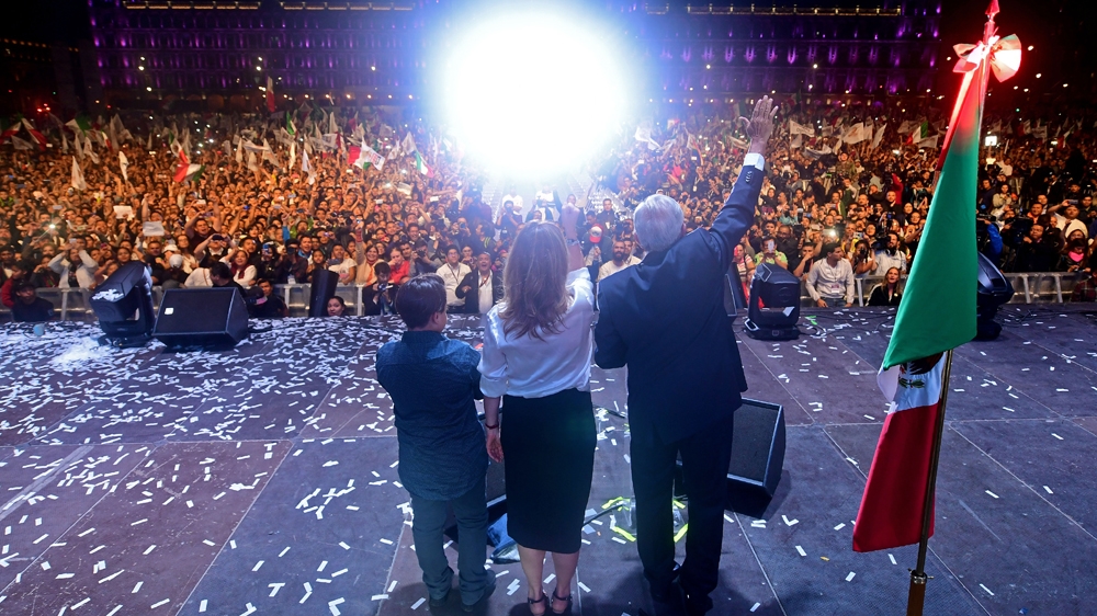 Lopez Obrador his wife Beatriz Gutierrez Muller cheer at Mexico's Zocalo Square after winning general elections [Pedro Pardo/AFP]