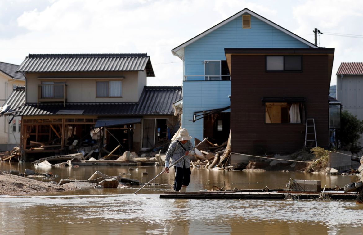 An elderly woman walks next to submerged and destroyed houses in a flooded area in Mabi town in Kurashiki, Okayama Prefecture, Japan, July 9, 2018. REUTERS/Issei Kato