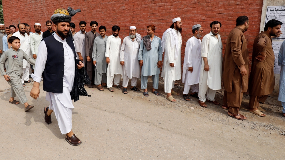 Men stand in line to cast their vote during the general election, outside a polling station in Peshawar [Fayaz Aziz/Reuters] 