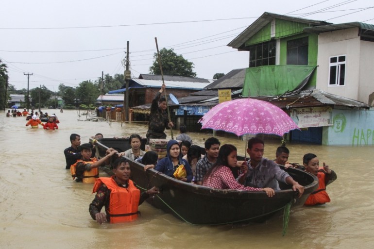 Members of Myanmar Rescue Team carry residents in a boat to travel along a flooded road in Bago, about 80 kilometers (50 miles) northeast of Yangon, Myanmar, Sunday, July 29, 2018. (AP Photo/Myo Kyaw