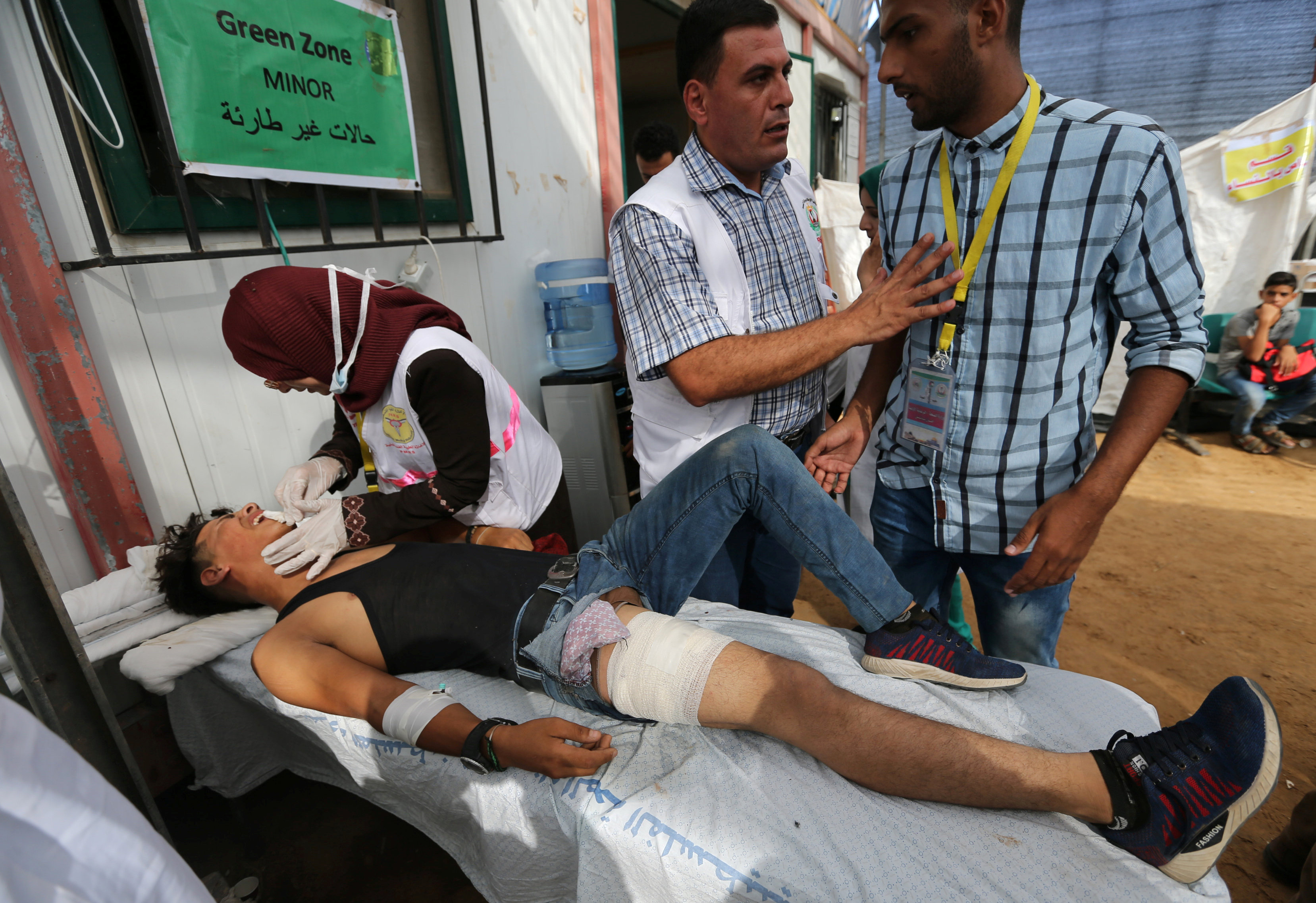 A medic tends to a wounded Palestinian during Friday's protest. [Ibraheem Abu Mustafa/Reuters]