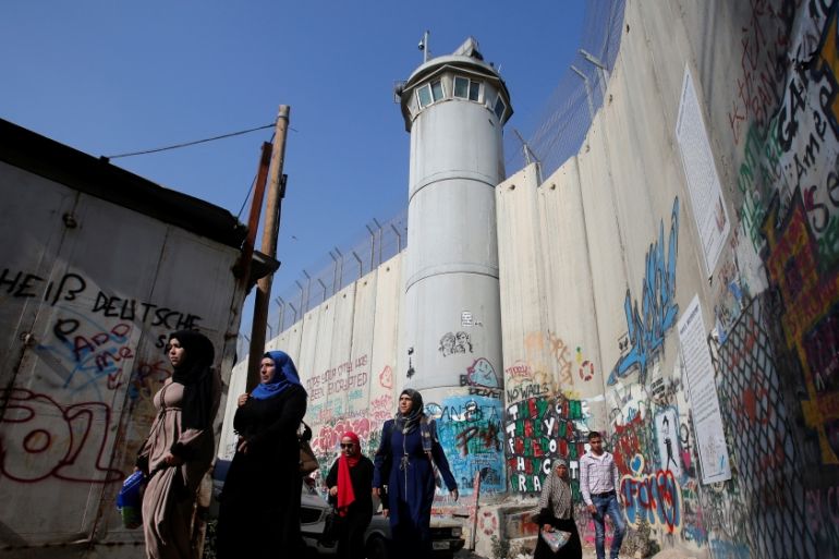 Palestinians pass by a section of the controversial Israeli barrier on their way to attend Friday prayer of the holy fasting month of Ramadan in Jerusalem''s Al-Aqsa mosque, in Bethlehem
