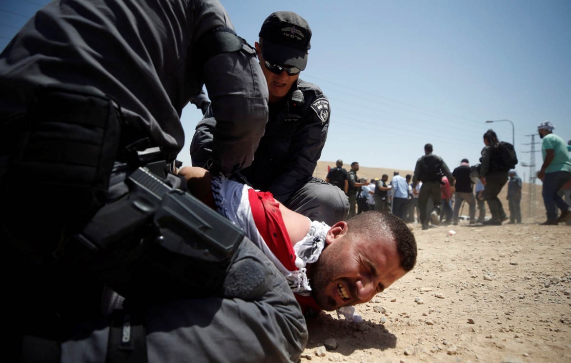 Israeli policemen detain a protester in the Palestinian Bedouin village of al-Khan al-Ahmar near Jericho in the occupied West Bank July 4, 2018. REUTERS/Mohamad Torokman