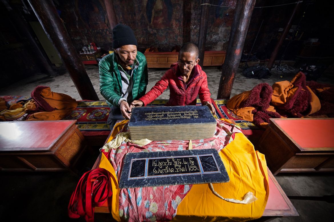 17. Chime Gurung, a Buddhist monk, shows Tashi Bista an ancient manuscript written in pure gold at a monastery in Lo Manthang, Nepal. Its sister book is believed to have been stolen from a stupa. This