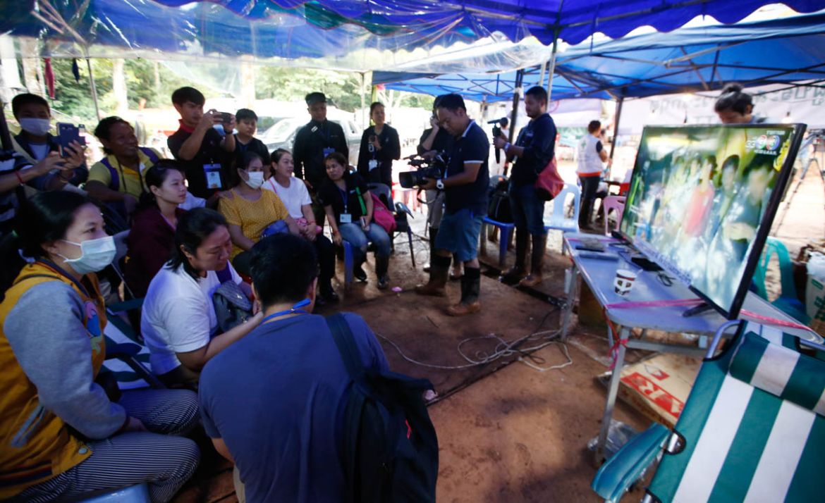 Family members of the 12 boys and their soccer coach watch a video clip of 12 boys on television after they were found alive, in Mae Sai, Chiang Rai province, in northern Thailand, Wednesday, July 4,