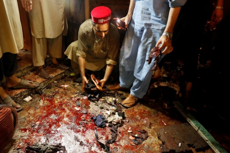 A man collects sandals of people who were killed after a suicide attack during an election campaign meeting in Peshawar