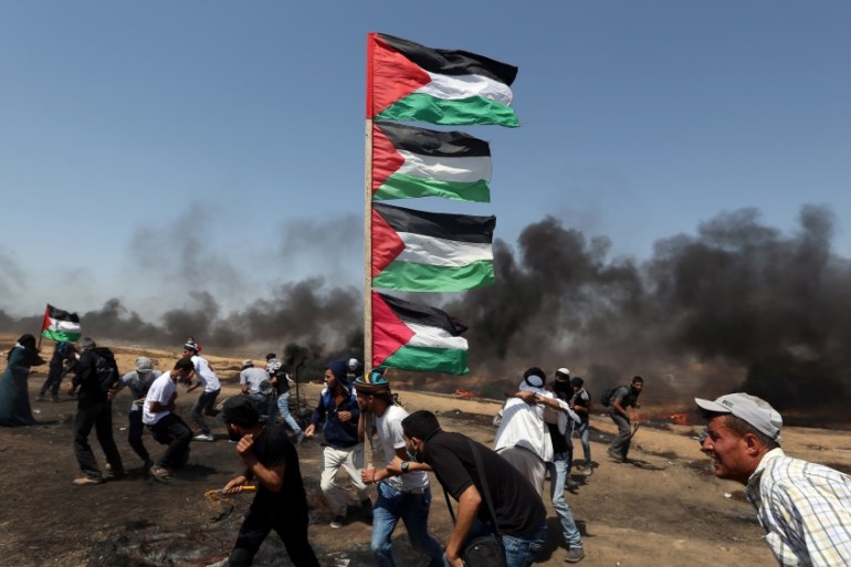 A demonstrator holds Palestinian flags as others run for cover during a protest marking al-Quds Day