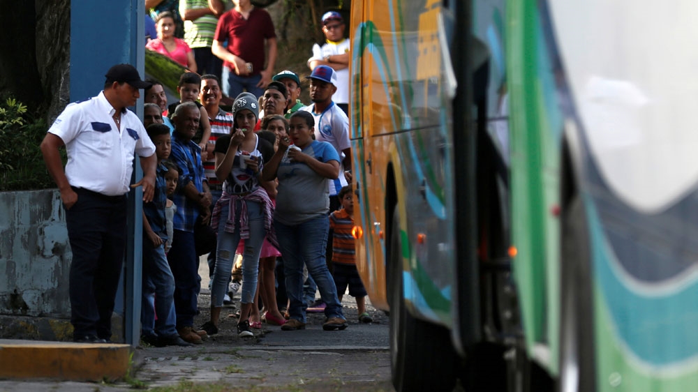 Relatives wait as a bus carrying people deported from the US arrive at an immigration facility in San Salvador [Jose Cabezas/Reuters]