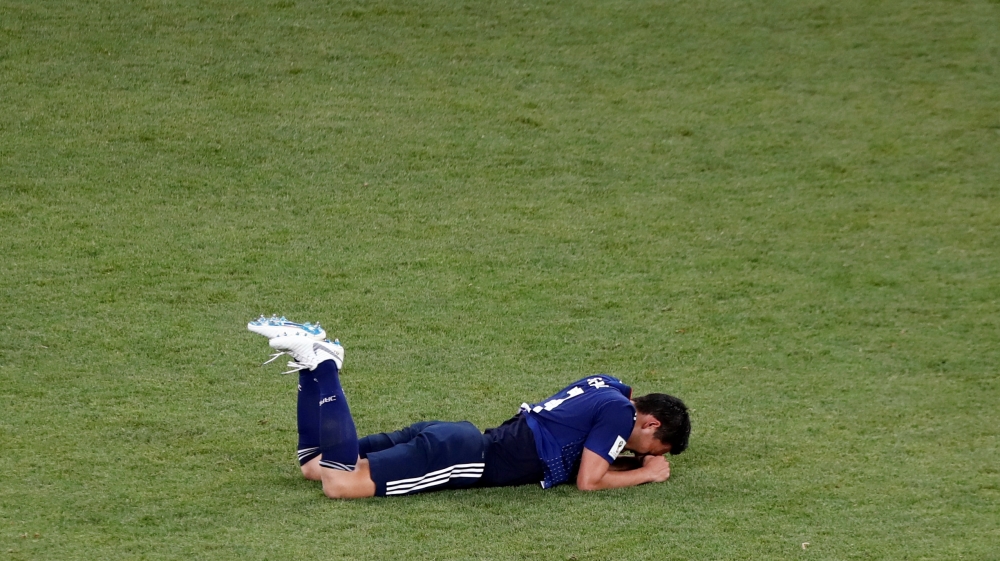 Players were devastated on the field after conceding a 94th-minute goal that sealed Japan's exit from the World Cup [Murad Sezer/Reuters]There was not much joy off the field either with fans in shock [Issei Kato/Reuters]