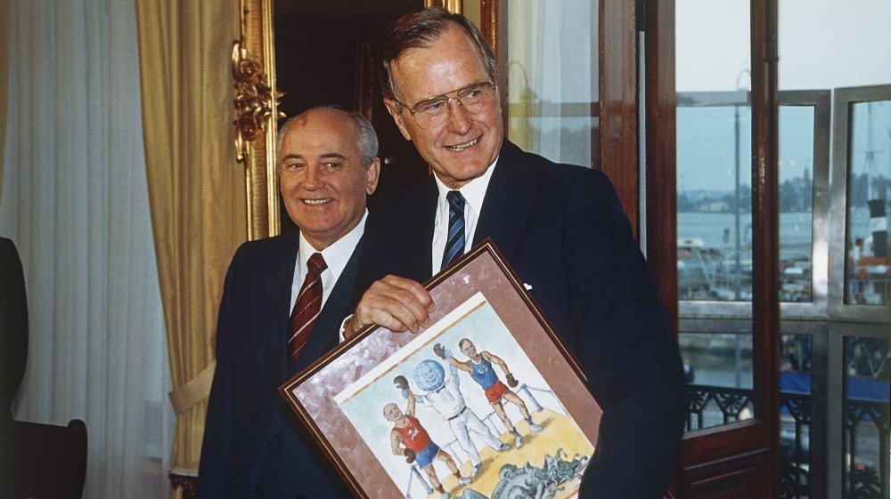 US President George Bush holds a framed cartoon presented to him by Soviet President Mikhail Gorbachev on September 9, 1990 in Helsinki. The cartoon shows Mr World holding up the hands of Bush and Gorbachev after their knockout of the Cold War [AP/Doug Mills]