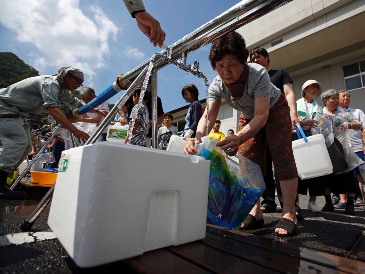 Local residents receive emergency water supply near a flooded area at Mihara Daini junior high school, which is acting as an emergency water supplying station, in Mihara, Hiroshima Prefecture, Japan,