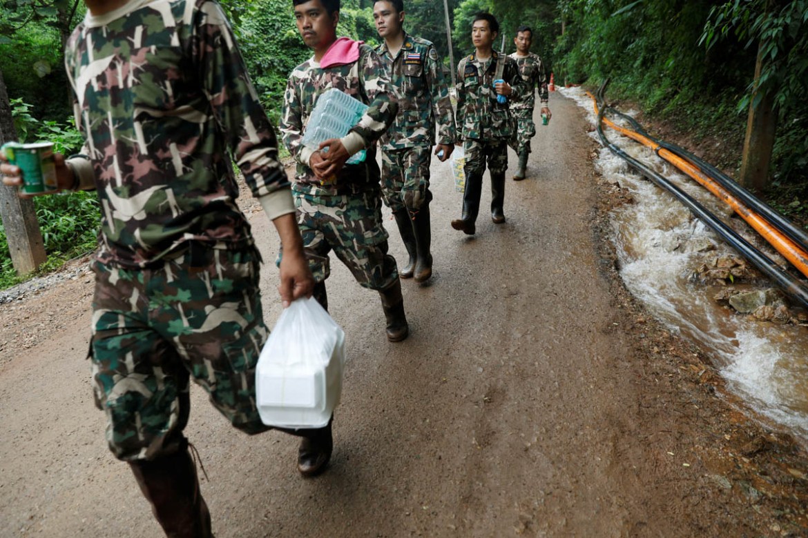 Rescue workers carry aid provisions near the Tham Luang cave complex, as members of an under-16 soccer team and their coach have been found alive according to local media, in the northern province of