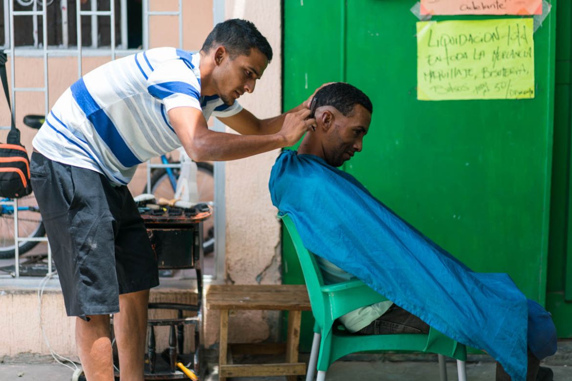 20180518_IrisEbert_Colombia-6 Luis* gives haircuts for 1,000 Colombian pesos, less than $1 USD, next to the Simon Bolivar Bridge near Cúcuta, Colombia, bordering Venezuela. His wife is in Venezuela, s