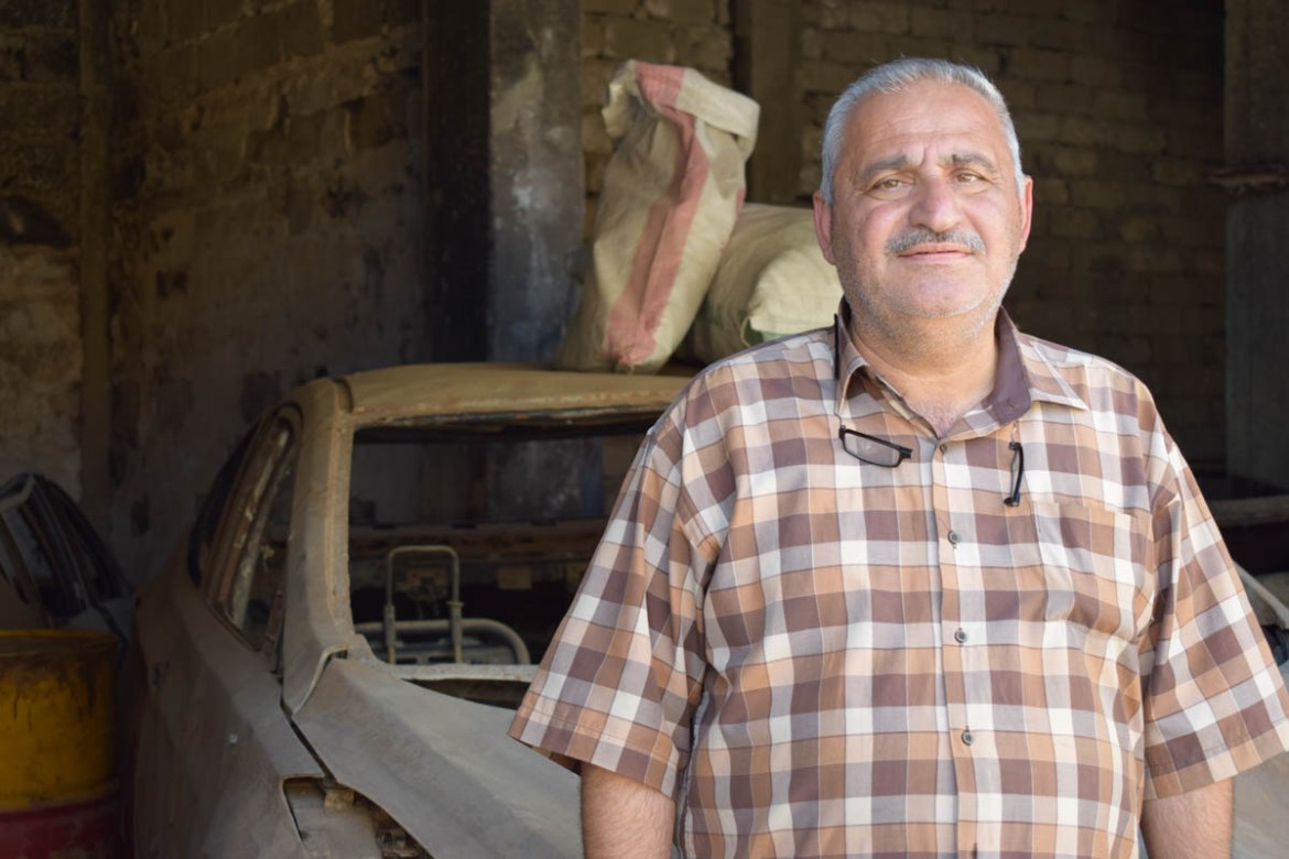 Photo 10 Firas stands in front of what is left of his car. Firas is the owner of a bakery shop in West Mosul. He came back to his neighbourhood one year ago, after the military operations ended. “Unti
