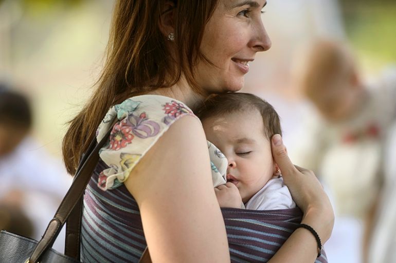 A woman holds her child at an event promoting the freedom of mothers to breastfeed in public, during World Breastfeeding Week at the Village Museum in Bucharest, Romania, Saturday, Aug. 6, 2016. (AP P