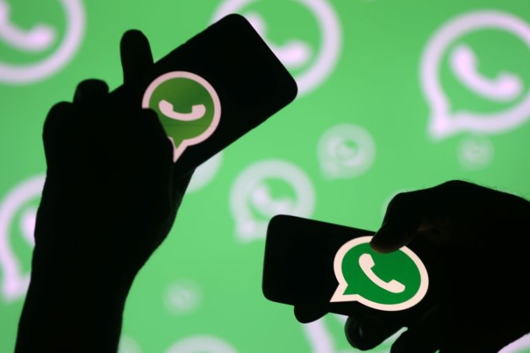Men pose with smartphones in front of displayed Whatsapp logo in this illustration September 14, 2017. [Dado Ruvic/Reuters]