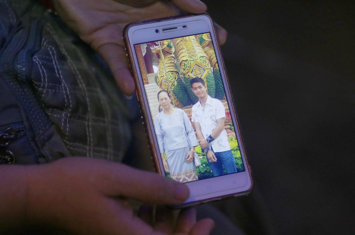 The aunt of coach Ekapol Chantawong shows a picture of the coach and his grandmother on a mobile phone screen, in Mae Sai, Chiang Rai province, in northern Thailand, Wednesday, July 4, 2018. With heav