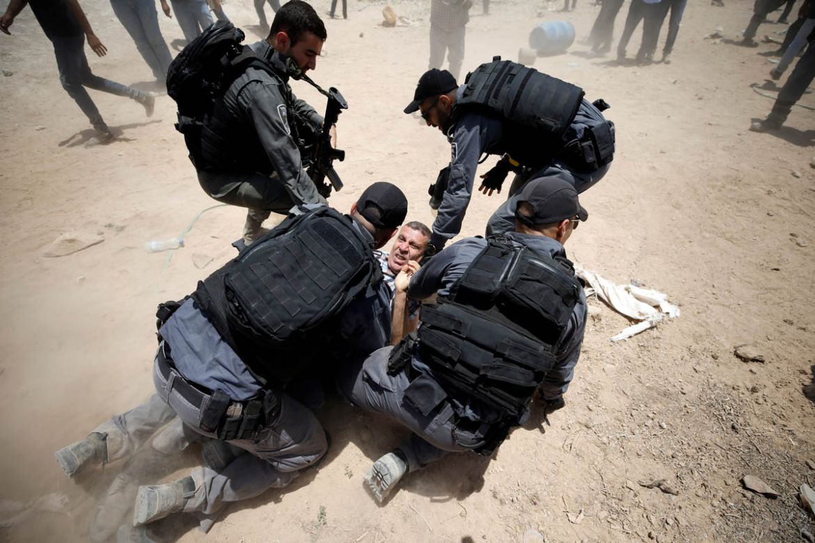 Israeli policemen detain a Palestinian in the Bedouin village of al-Khan al-Ahmar near Jericho in the occupied West Bank July 4, 2018. REUTERS/Mohamad Torokman