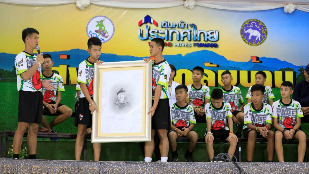 The boys held a portrait of diver Saman Kunan who died during the rescue operation [Soe Zeya Tun/Reuters]