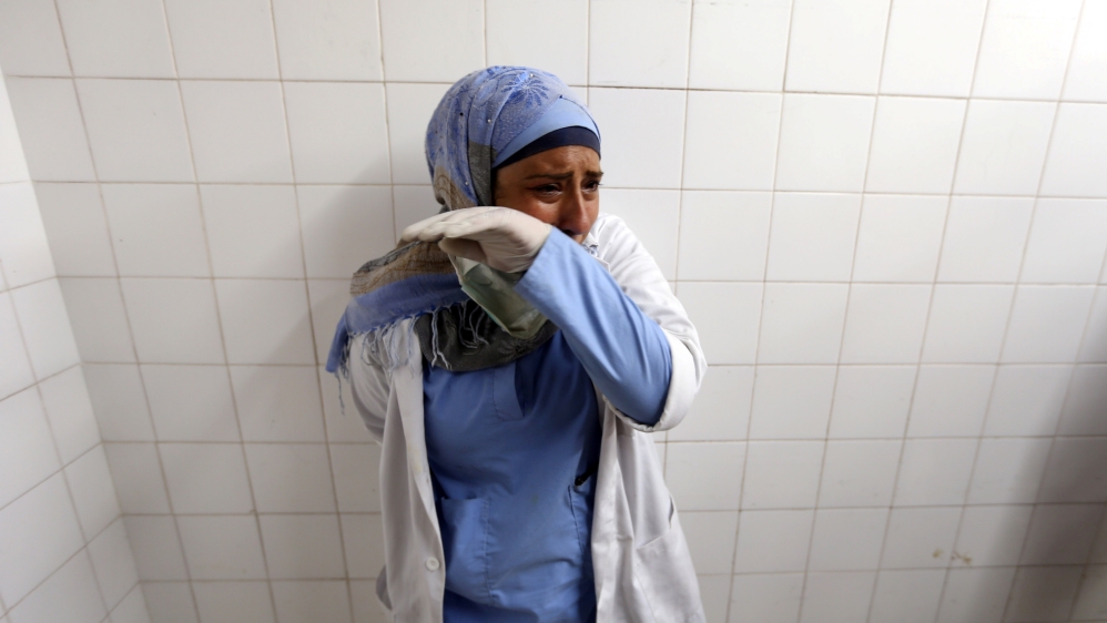 A colleague of Al-Najjar reacts to news of her death at a hospital in southern Gaza [Ibraheem Abu Mustafa/Reuters]