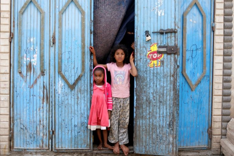 Girls displaced from Yemen''s northwestern province of Saada stand with their mother outside a temporary shelter in Sanaa, Yemen