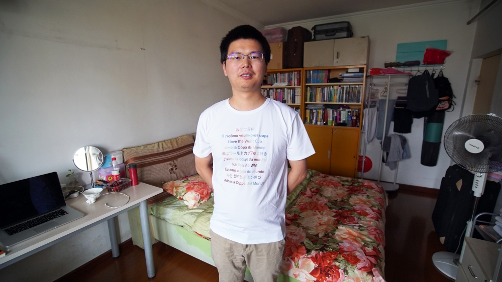 Jun Tang poses in a t-shirt he and his friends will be wearing at the World Cup [Katrina Yu/Al Jazeera]