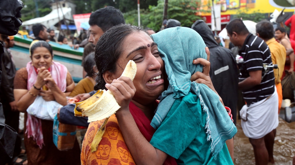 A woman is evacuated from a flood-stricken area [Sivaram V/Reuters]