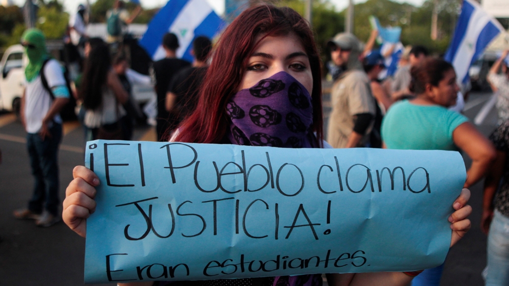 A sign reads 'The people clamour for justice! They were students' at a May protest [File: Oswaldo Rivas/Reuters]