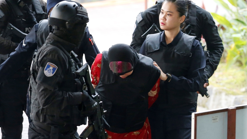 Siti Aisyah is brought into court by Malaysian police officers. [Lai Seng Sin/Reuters]