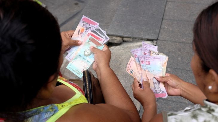 Women look at new Bolivar Soberano (Sovereign Bolivar) bills, after they withdrew them from an ATM at a branch of Banco de Venezuela in Caracas
