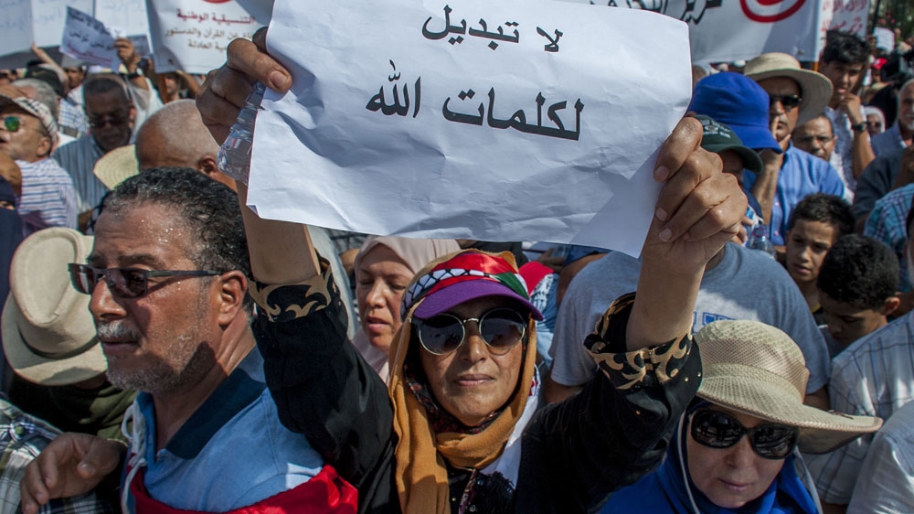 A demonstrator in Tunis with a sign that reads 'No to change God's speech' [Hassene Dridi/AP]