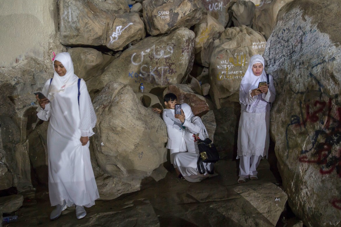 Muslim pilgrims take photos at the Jabal Al Rahma holy mountain, or the mountain of forgiveness, at Arafat for the annual hajj pilgrimage outside the holy city of Mecca, Saudi Arabia, Monday, Aug. 20,