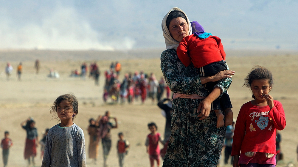 Displaced people from the minority Yazidi sect walk towards the Syrian border on the outskirts of Sinjar mountain on August 11, 2014 [Rodi Said/Reuters]