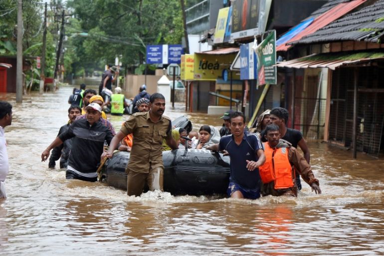 Rescuers evacuate people from a flooded area to a safer place in Aluva