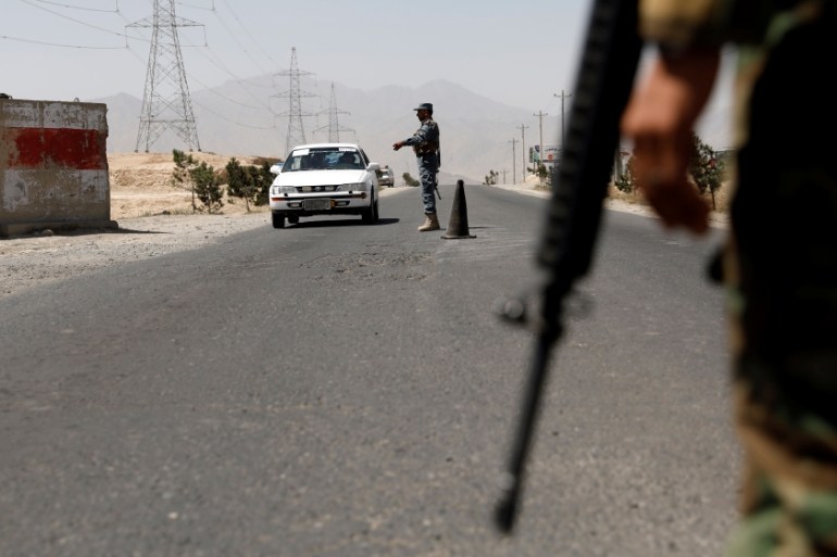 An Afghan policeman keeps watch at a checkpoint on the Ghazni highway, in Maidan Shar, the capital of Wardak province, Afghanistan