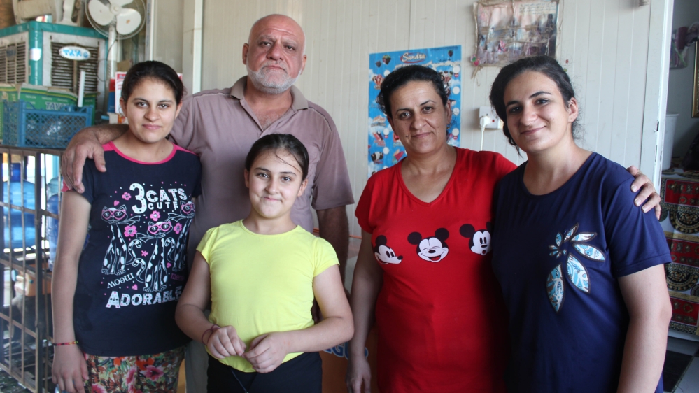 Samir Petrus, 50, stands with his wife Evelyn and three of his five daughters at their shop in the camp [Arwa Ibrahim/Al Jazeera] 
