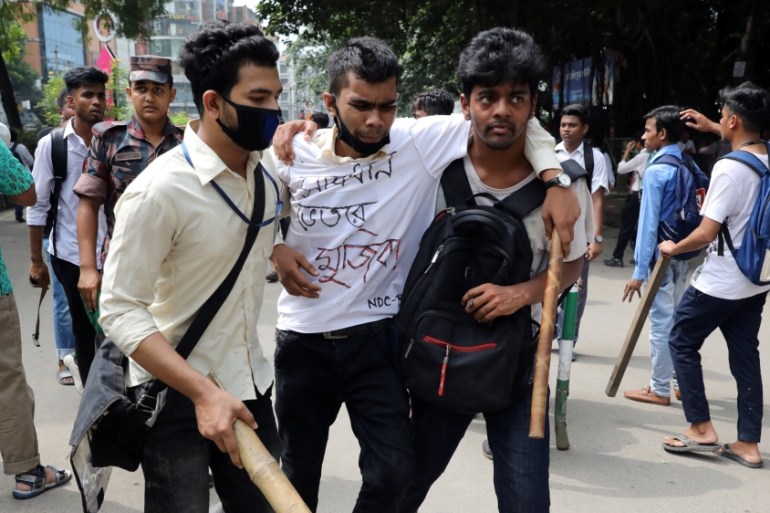 An injured student is helped during clashes with unidentified miscreants while they are protesting over recent traffic accidents that killed a boy and a girl, in Dhaka