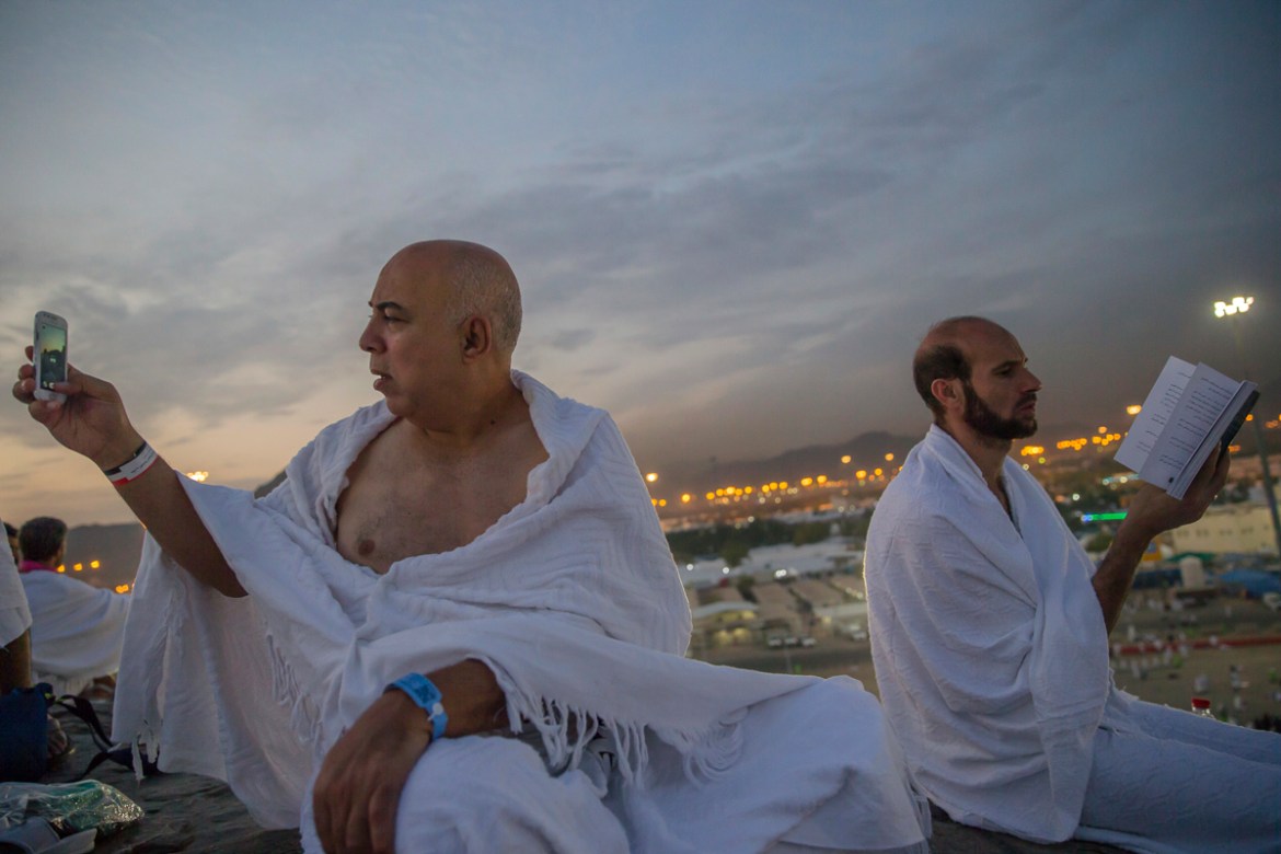 A Muslim pilgrim prays as another pilgrim takes a photo, at Jabal Al Rahma holy mountain, or the mountain of forgiveness, at Arafat for the annual hajj pilgrimage, outside the holy city of Mecca, Saud